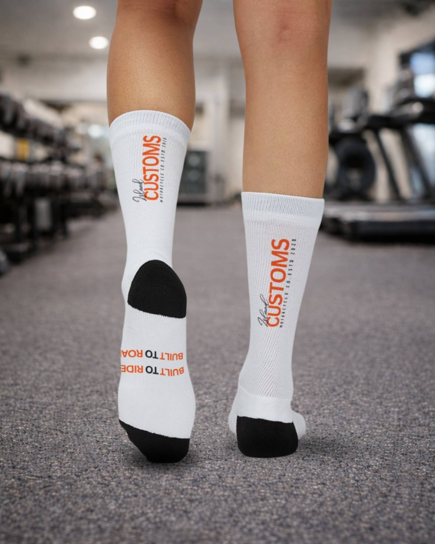 White socks with orange text worn by a person in a gym setting