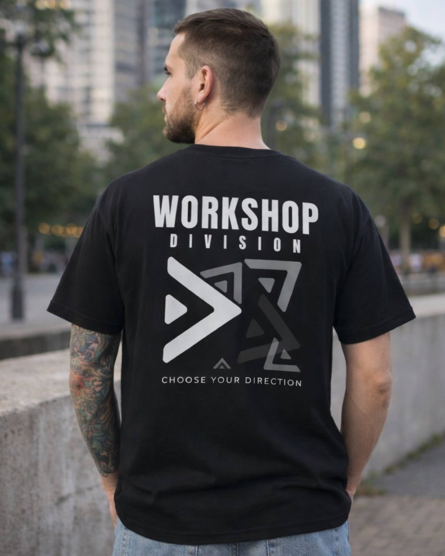Man wearing a black t-shirt with 'Workshop Division' logo and text outdoors.