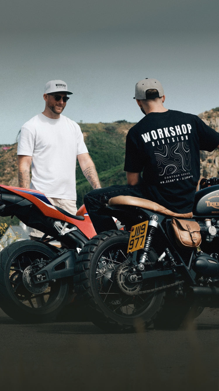 Two men standing next to custom motorcycles with a scenic background