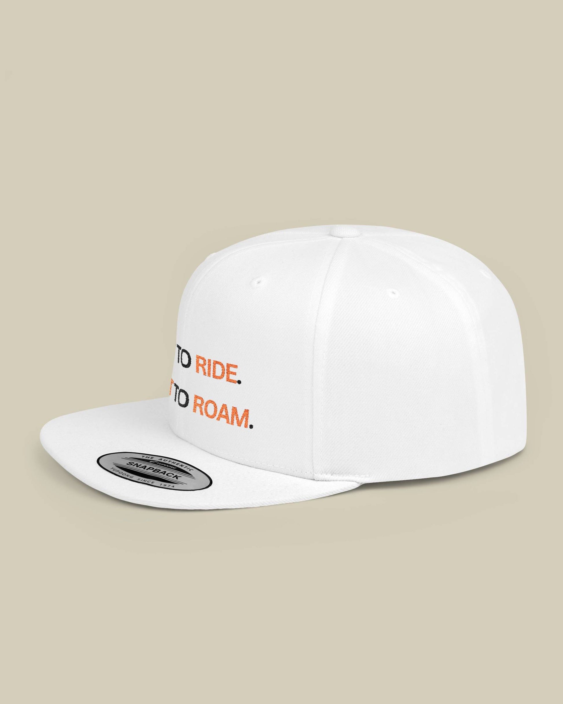 White cap with 'Ride to Roam' text on a beige background