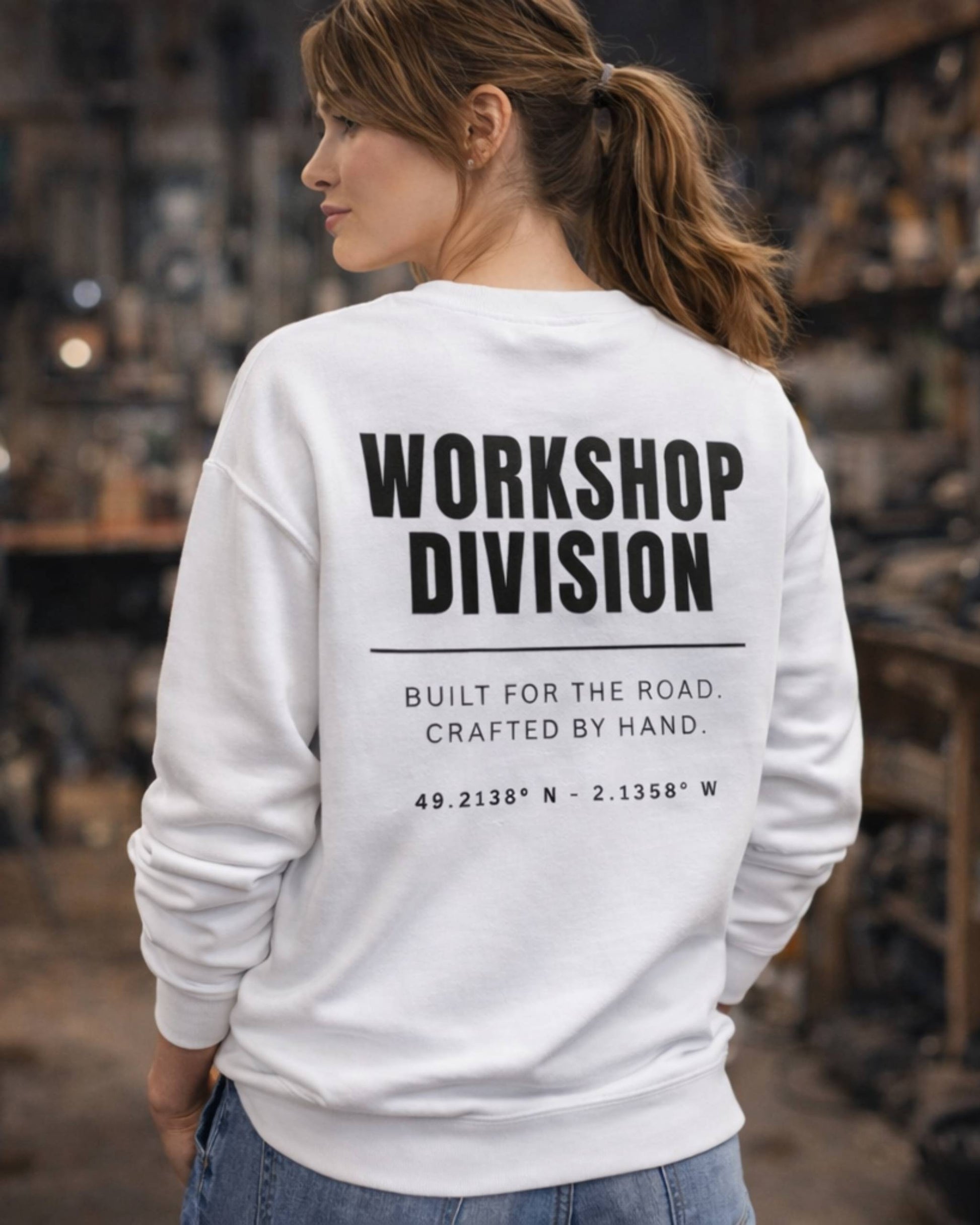 Person wearing a white sweatshirt with 'Workshop Division' text in a workshop setting