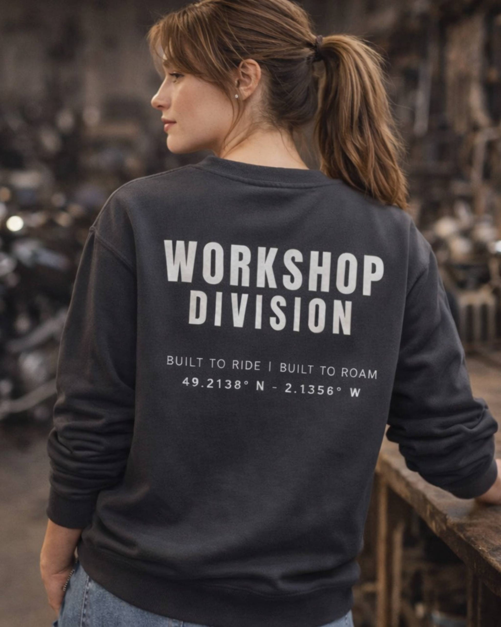 Person wearing a black sweatshirt with 'Workshop Division' text in an industrial setting