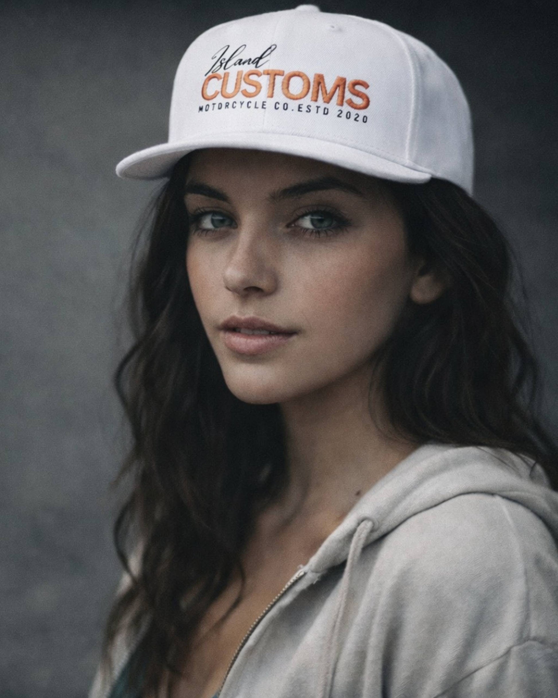 Woman wearing a white cap with 'Bland Customs' branding against a dark background