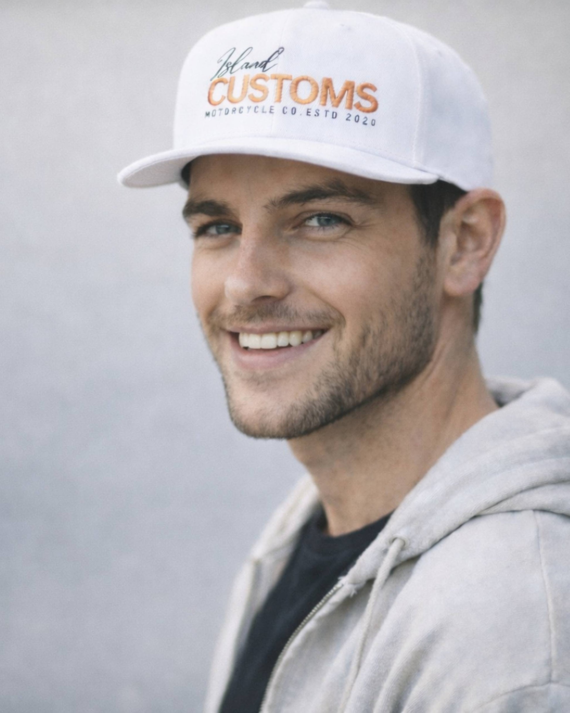 Man wearing a white cap with 'Blueline Customs' branding against a plain background