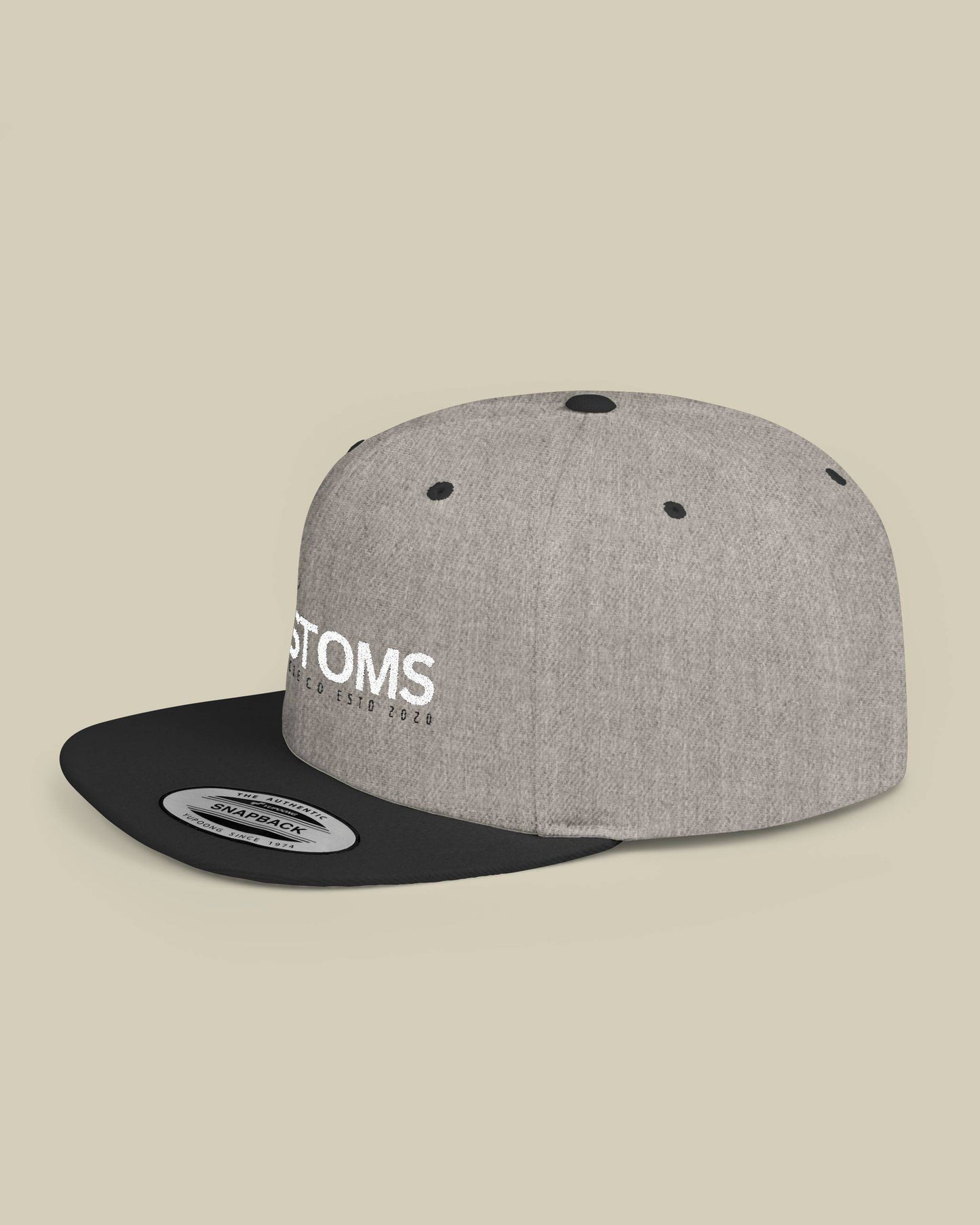 Gray and black cap with 'STOMS' logo on a beige background