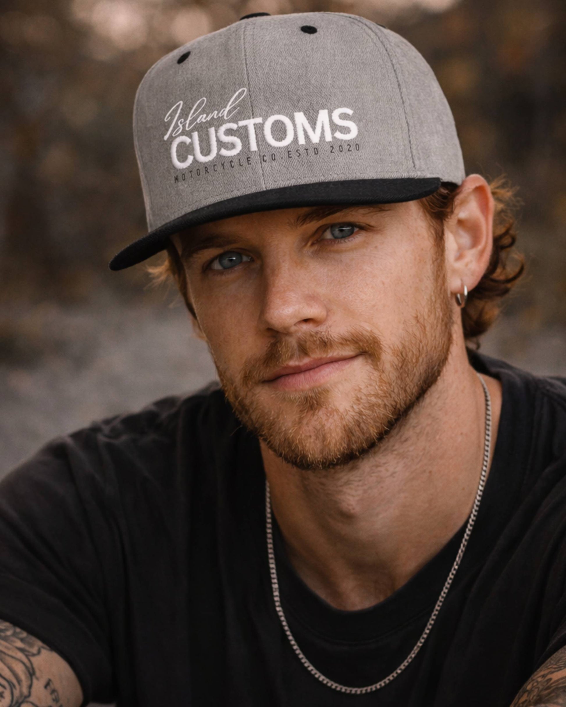 Man wearing a gray 'Island Customs' cap with a blurred natural background