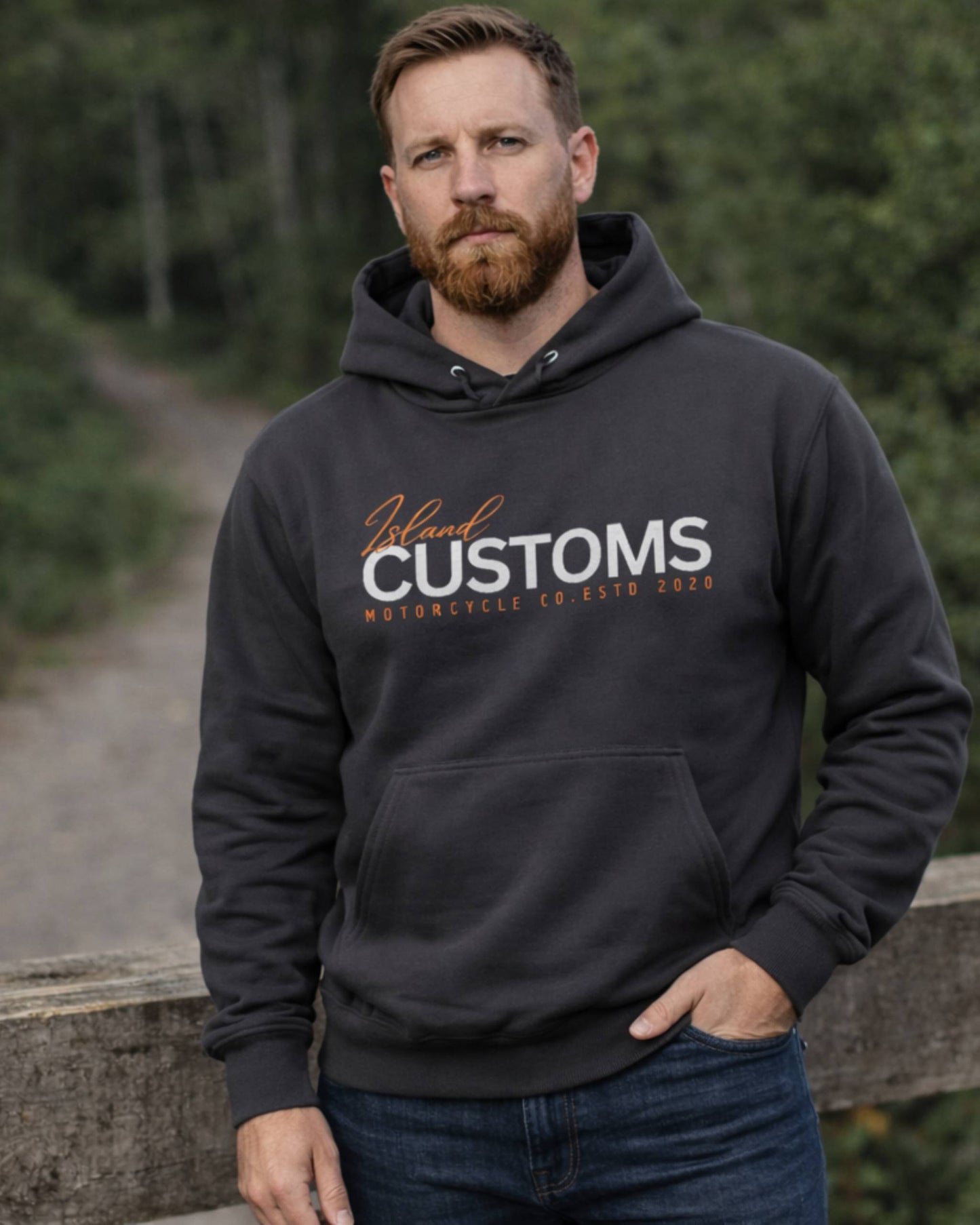 Man wearing a black hoodie with 'Island Customs' text outdoors