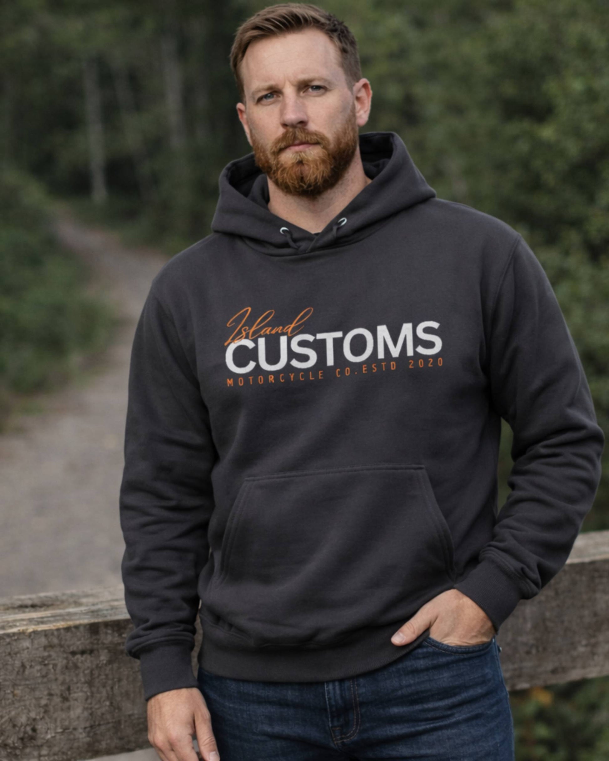 Man wearing a black hoodie with 'Island Customs' text outdoors