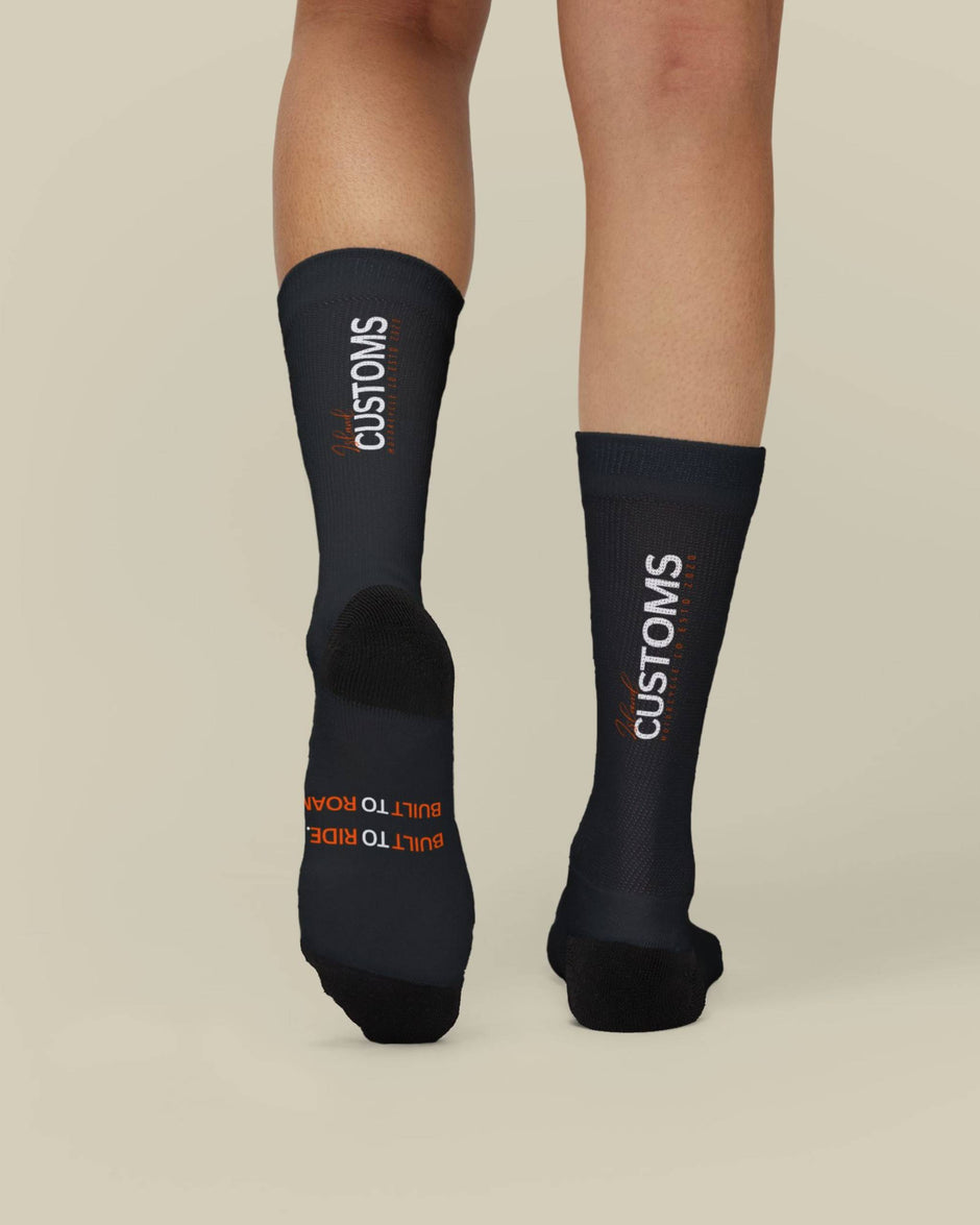 Black socks with 'CUSTOMS' branding on a beige background