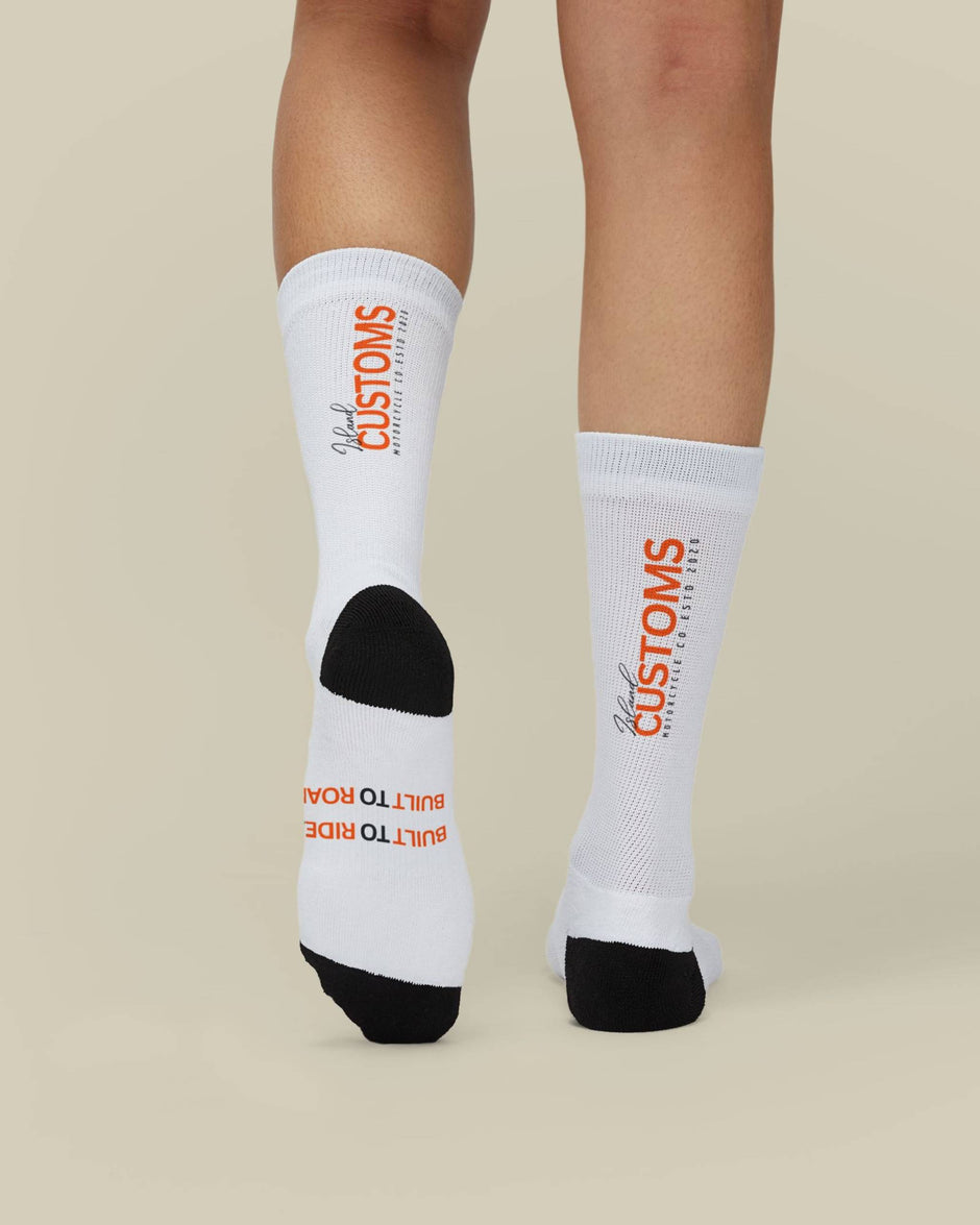 White socks with orange text worn by a person on a beige background