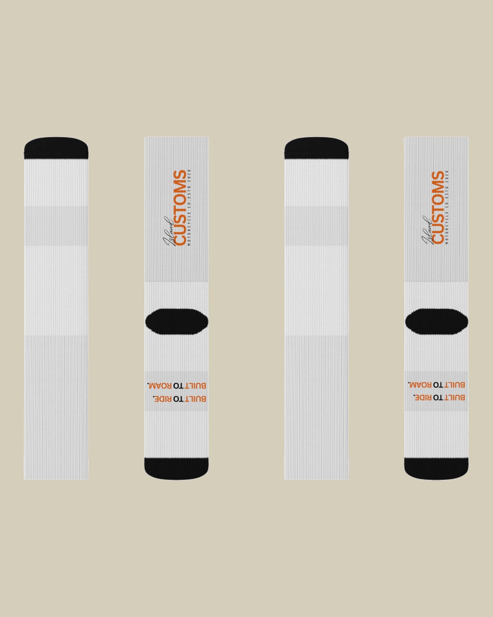 Four white socks with black toes and heels on a beige background, featuring 'Customs' branding.