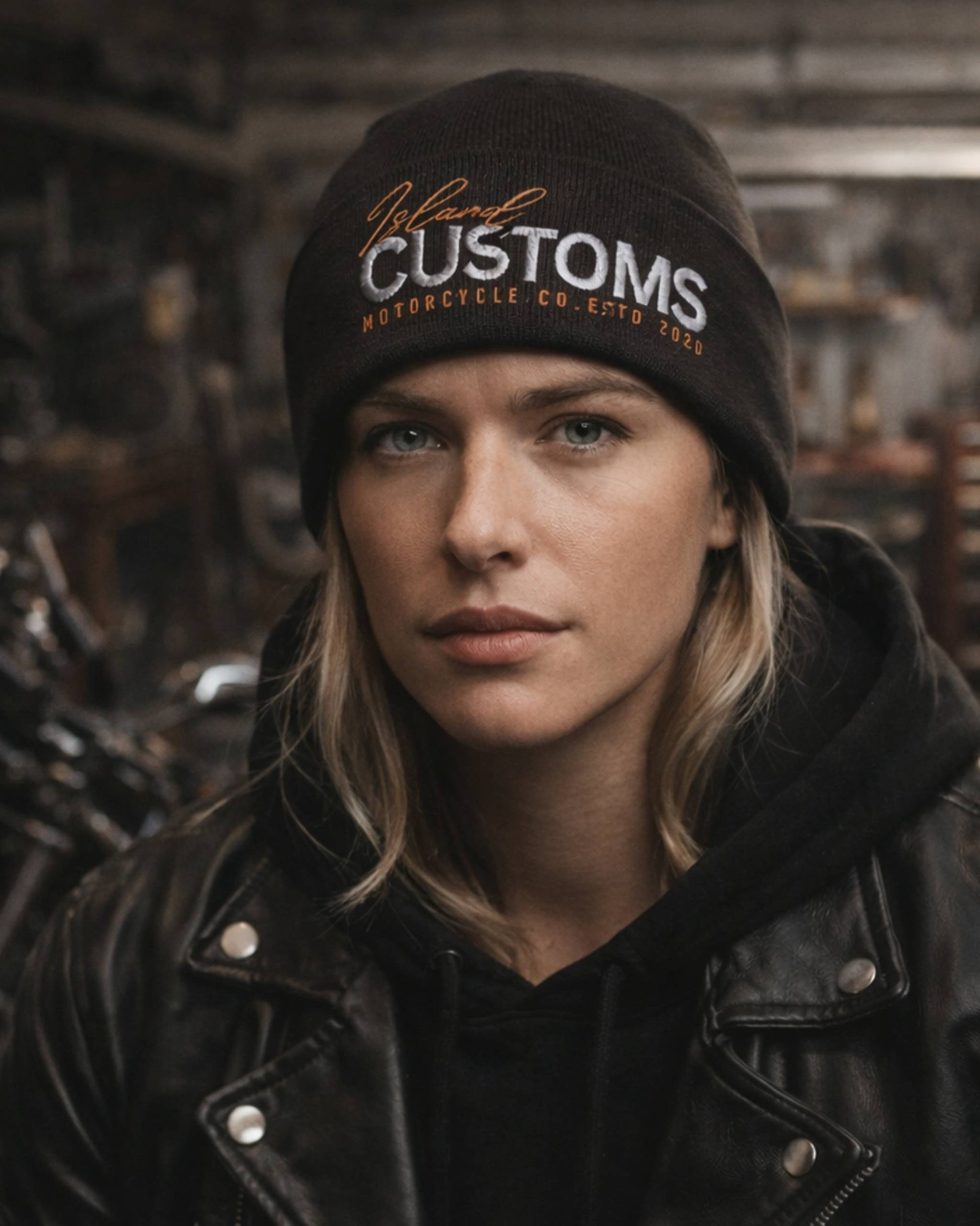 Person wearing a black beanie with 'Customs' branding against a blurred background