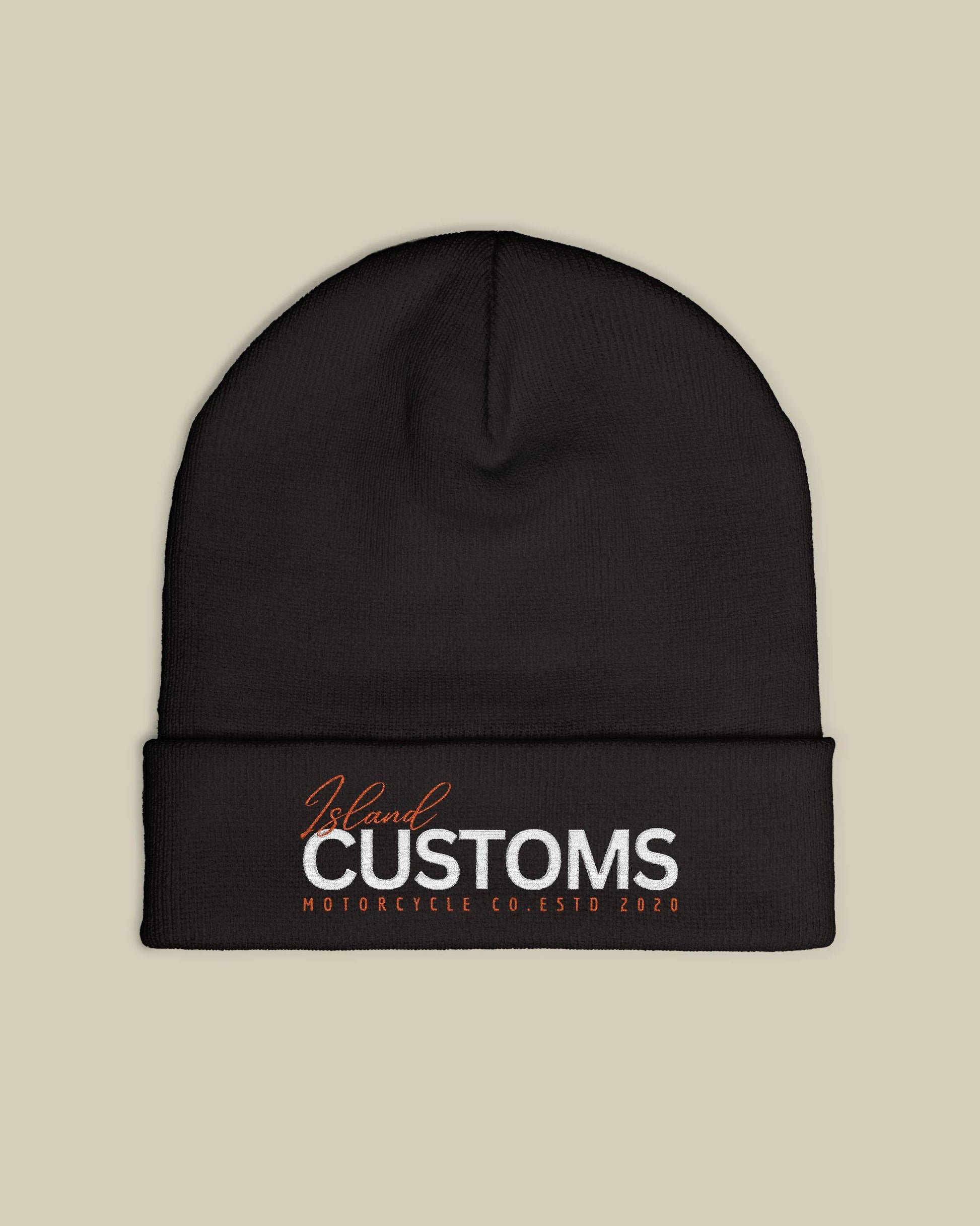 Black beanie with 'Customs' logo on a beige background