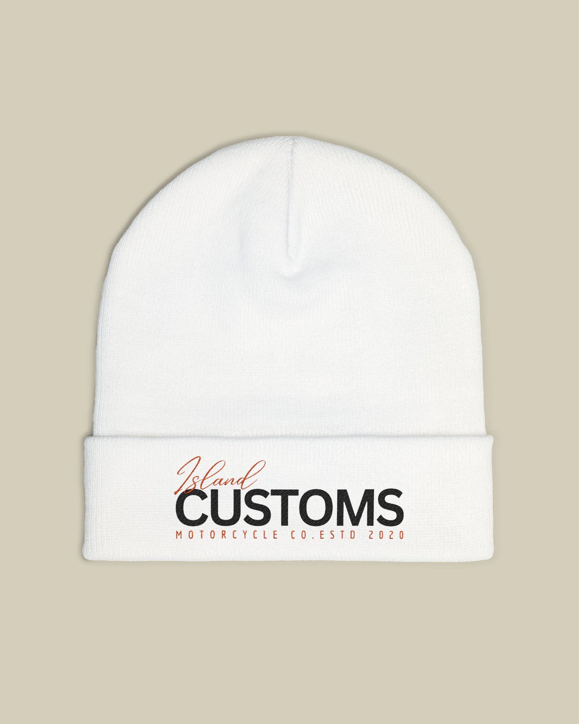 White beanie with 'Customs' logo on a beige background