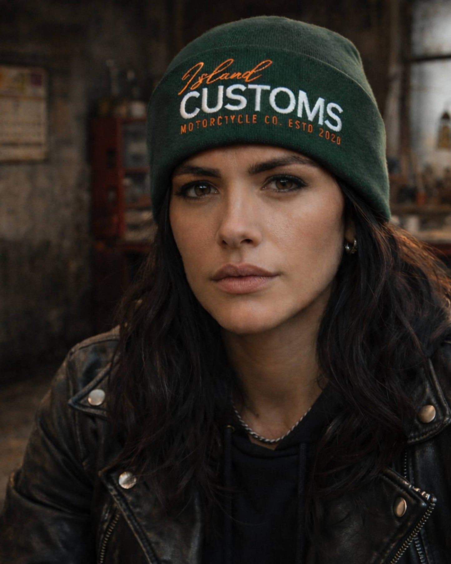 Woman wearing a green 'Island Customs' beanie in an indoor setting