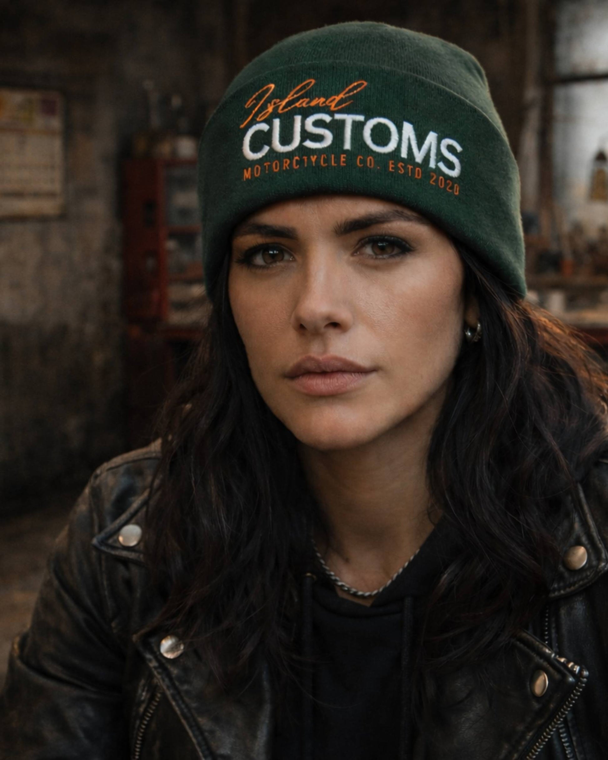 Woman wearing a green 'Island Customs' beanie in an indoor setting