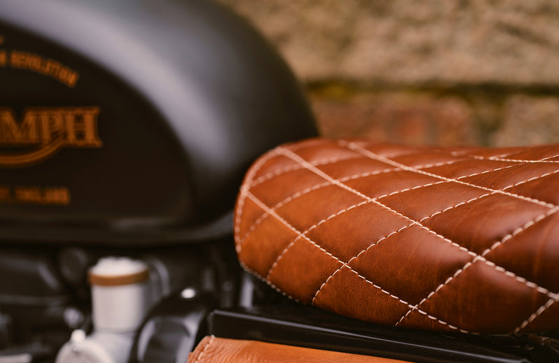 Close-up of a brown quilted motorcycle seat with a blurred background