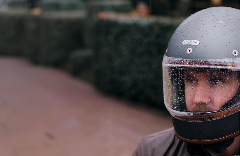 Person wearing a wet motorcycle helmet with a blurred background