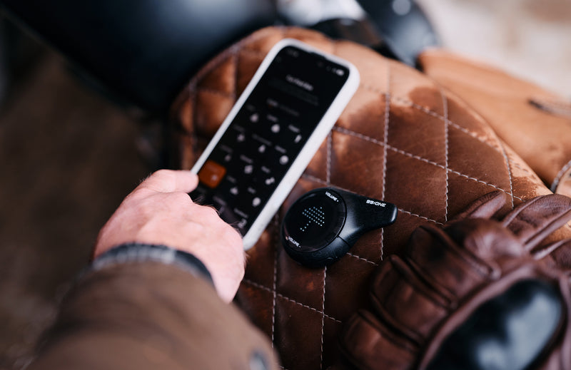 Hand holding a remote control on a brown leather surface