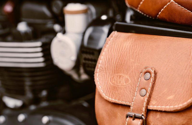 Brown leather saddlebag of a motorcycle with a blurred background