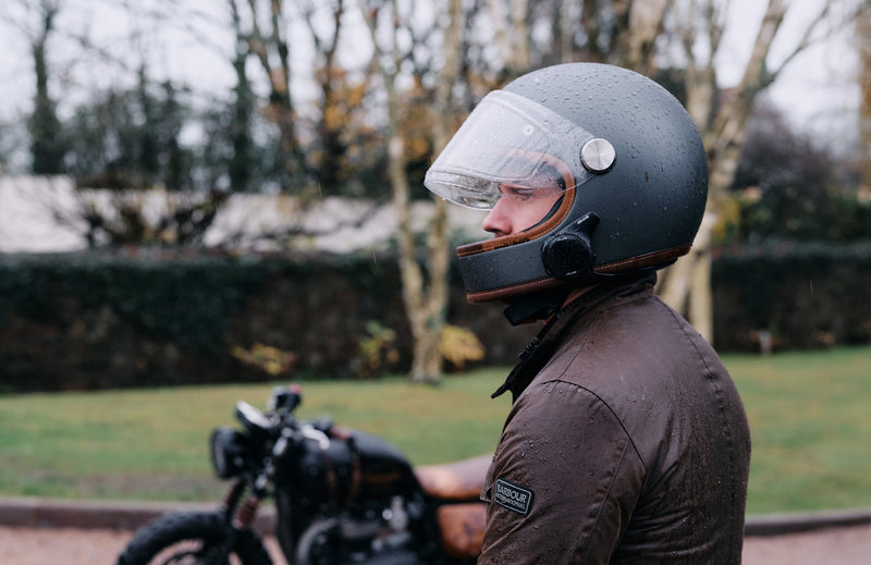 Person wearing a motorcycle helmet with a clear visor outdoors