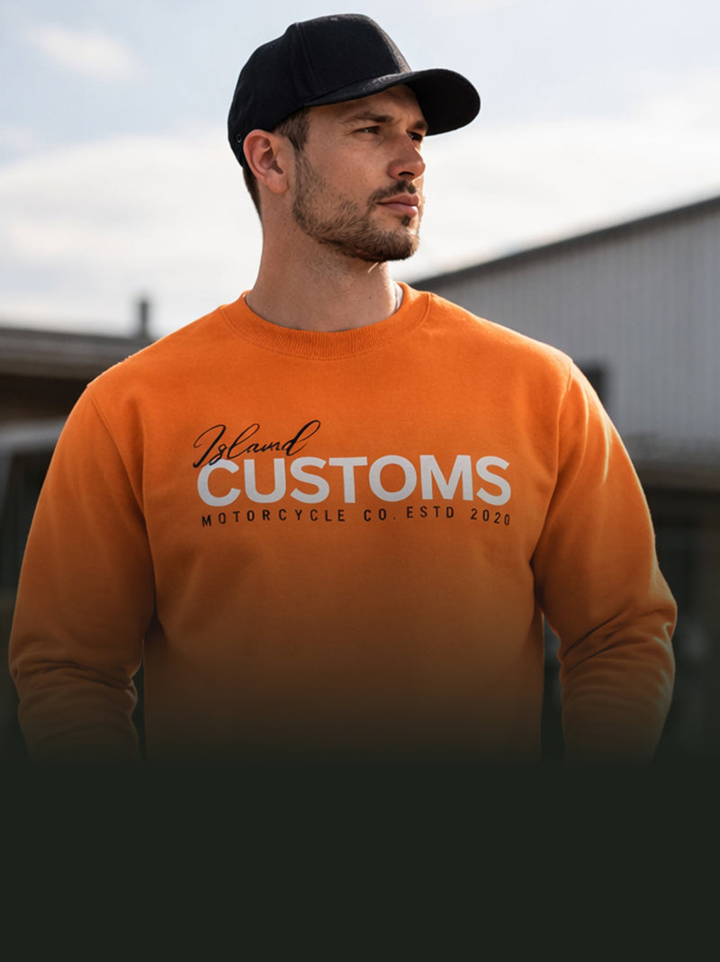 Man wearing an orange sweatshirt with 'Blain Customs' text, standing outdoors.