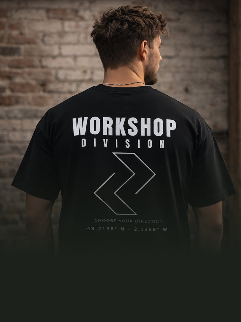 Man wearing a black t-shirt with 'Workshop Division' text and logo against a brick wall.
