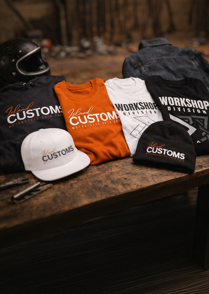 Collection of 'Workshop Customs' branded clothing and accessories on a wooden surface.