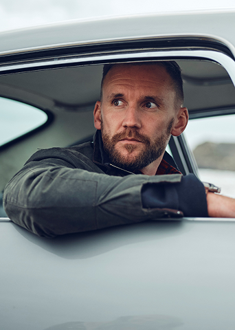 Man leaning out of a car window, looking surprised or intrigued.