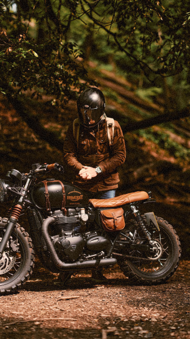 Person sitting on a motorcycle in a forest setting