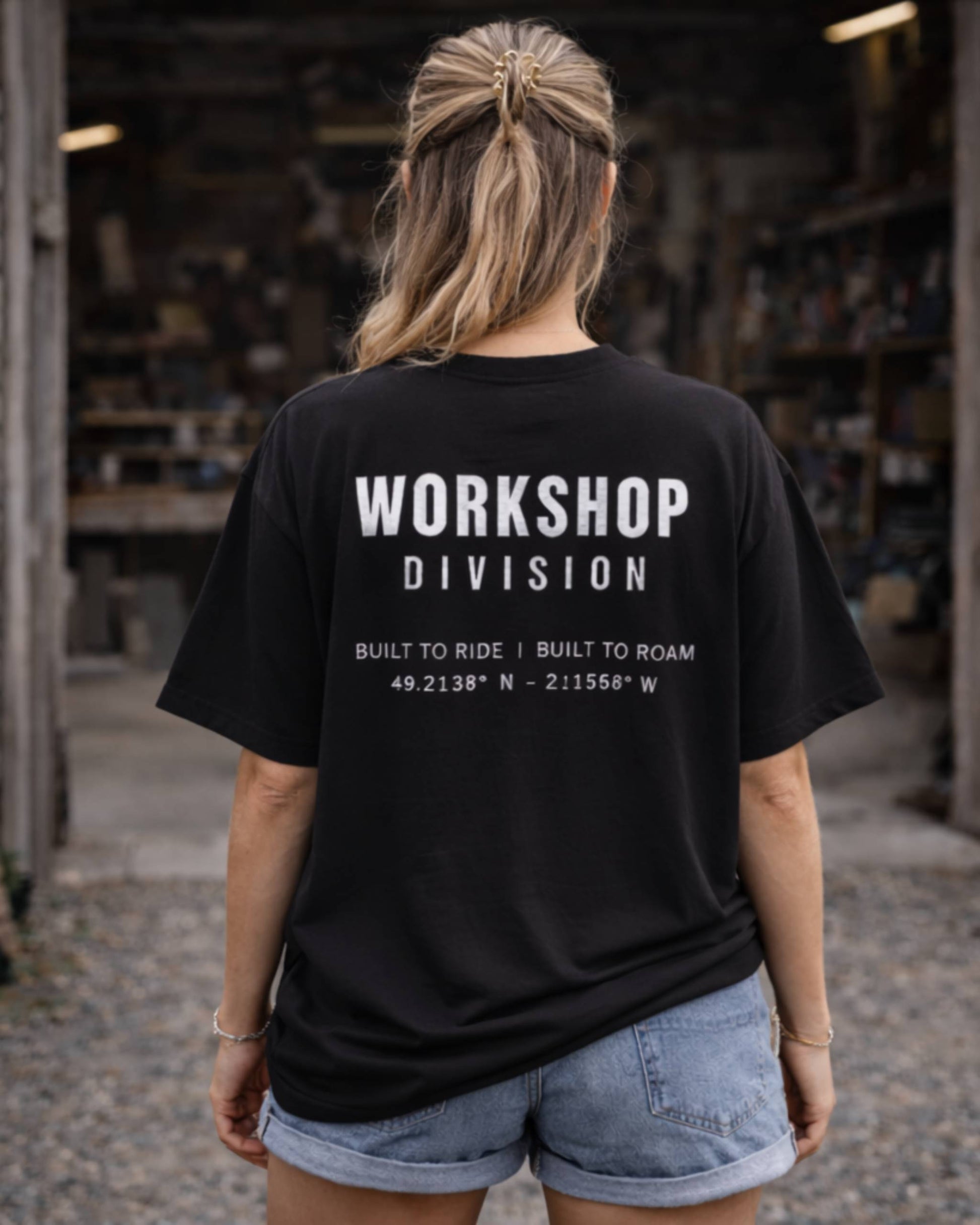 Person wearing a black t-shirt with 'Workshop Division' text in a workshop setting