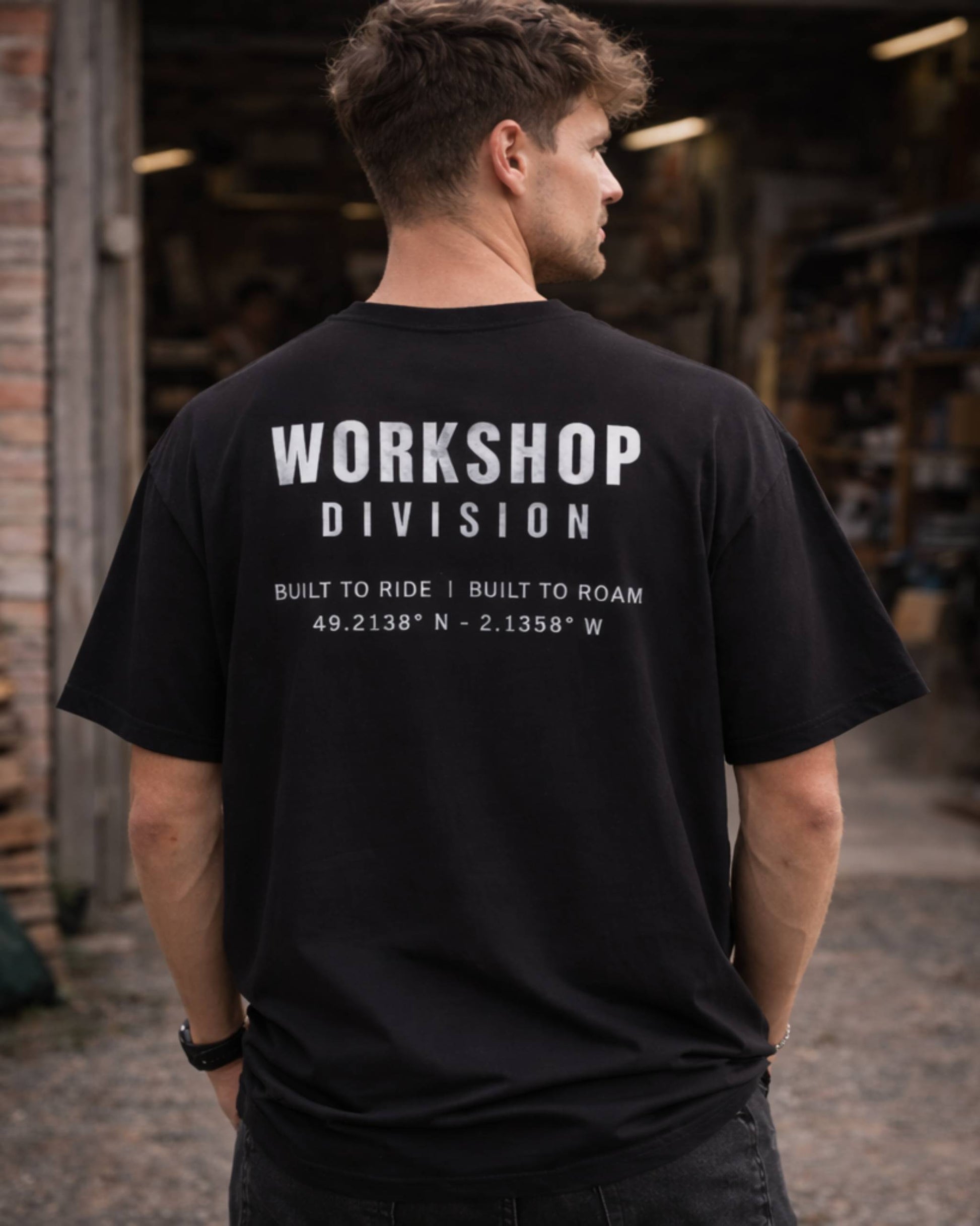 Person wearing a black t-shirt with 'Workshop Division' text in an indoor setting.
