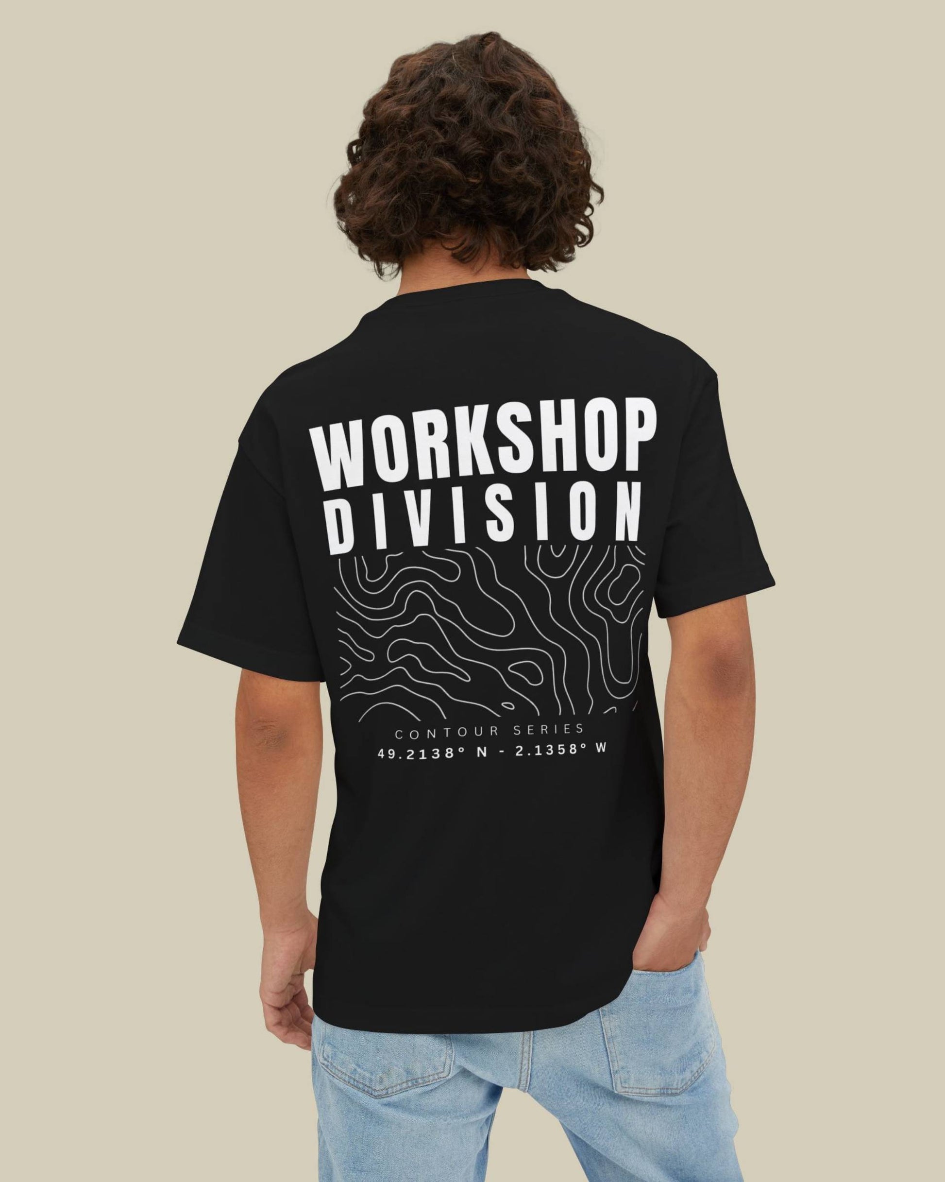 Person wearing a black t-shirt with 'Workshop Division' text on the back against a beige background