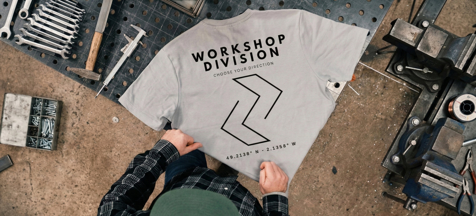 Gray t-shirt with 'Workshop Division' text on a workbench with tools.