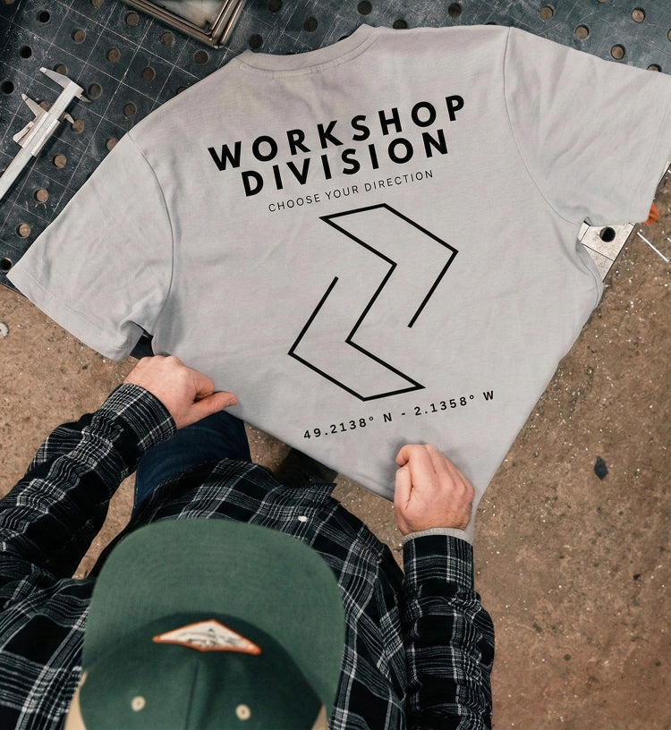 Gray t-shirt with 'Workshop Division' text and design on a workshop floor.