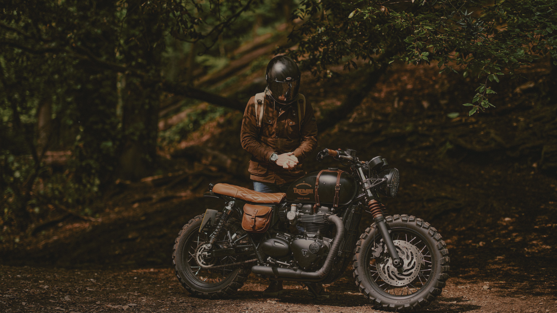 Person sitting on a motorcycle in a forest setting