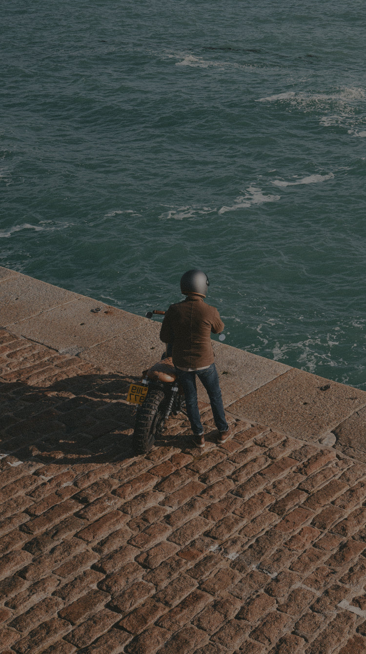 Person standing on a stone pier overlooking the ocean
