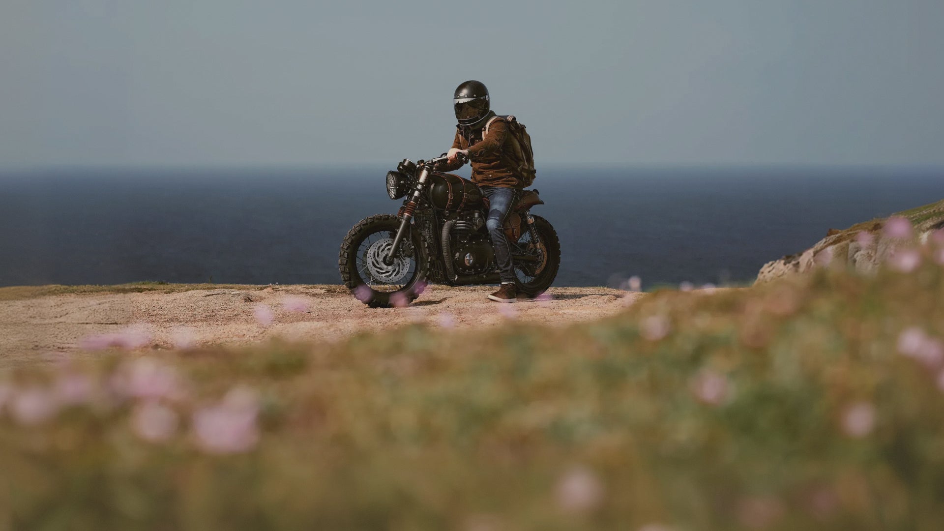 Person riding a motorcycle on a cliff with ocean view