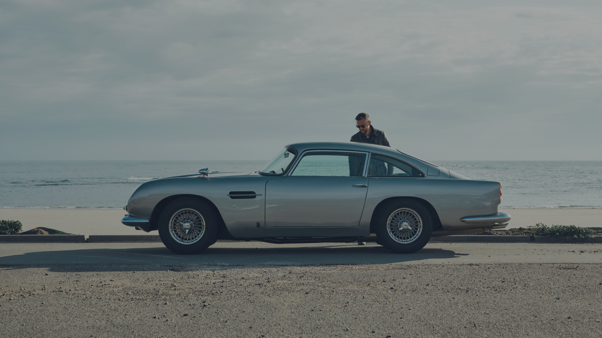 Vintage car on a beach with a person standing nearby