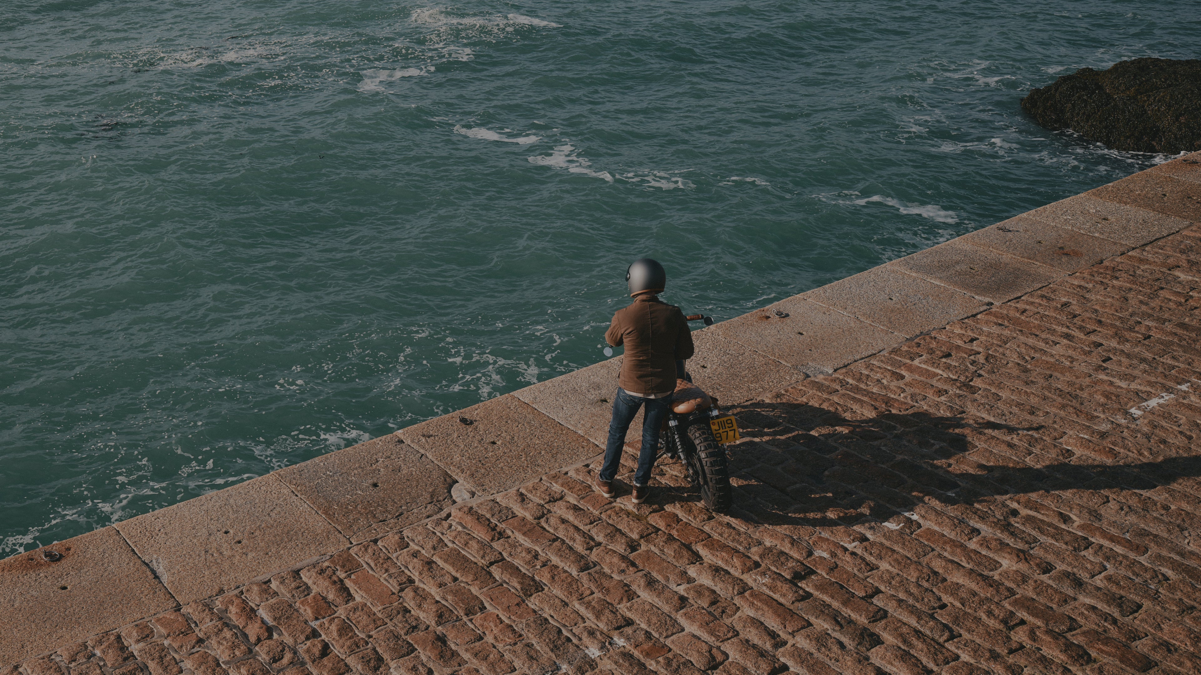 Person sitting on a ledge overlooking the ocean