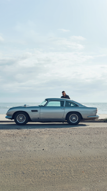 Vintage car on a beach with a person standing nearby