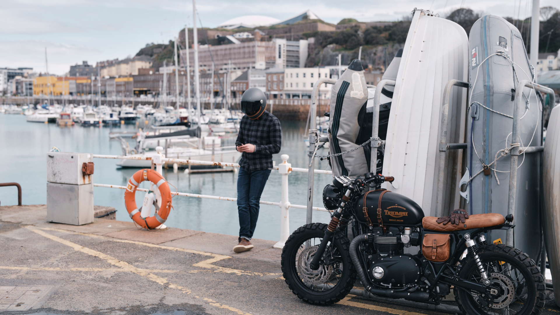 Motorcycle parked by a dock with people in the background