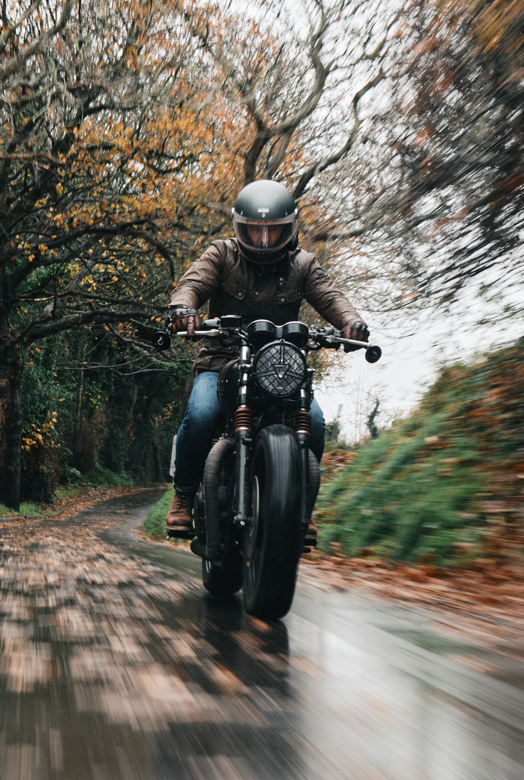 Person riding a motorcycle on a tree-lined road