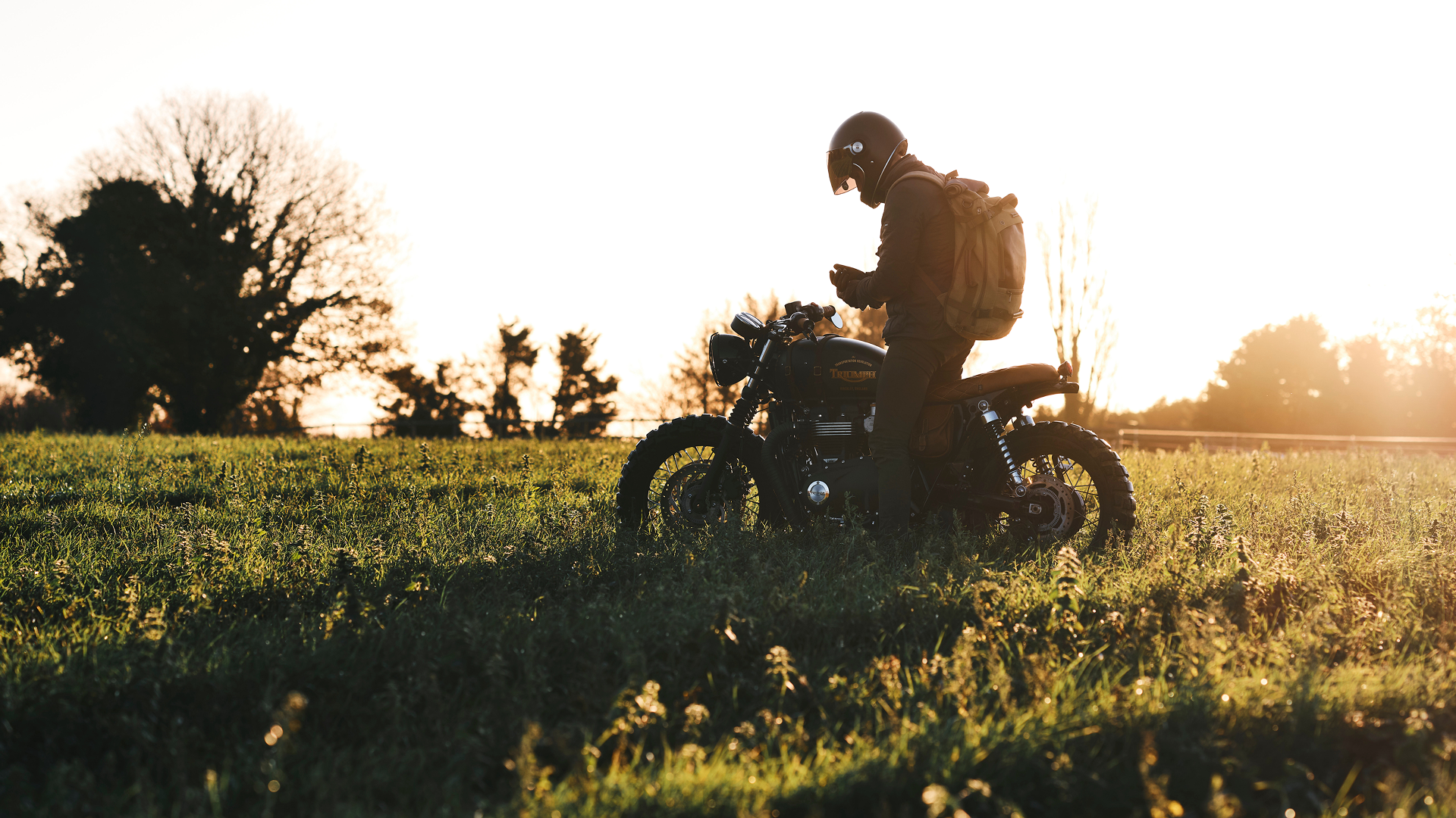 Person on a motorcycle in a field with sunset lighting