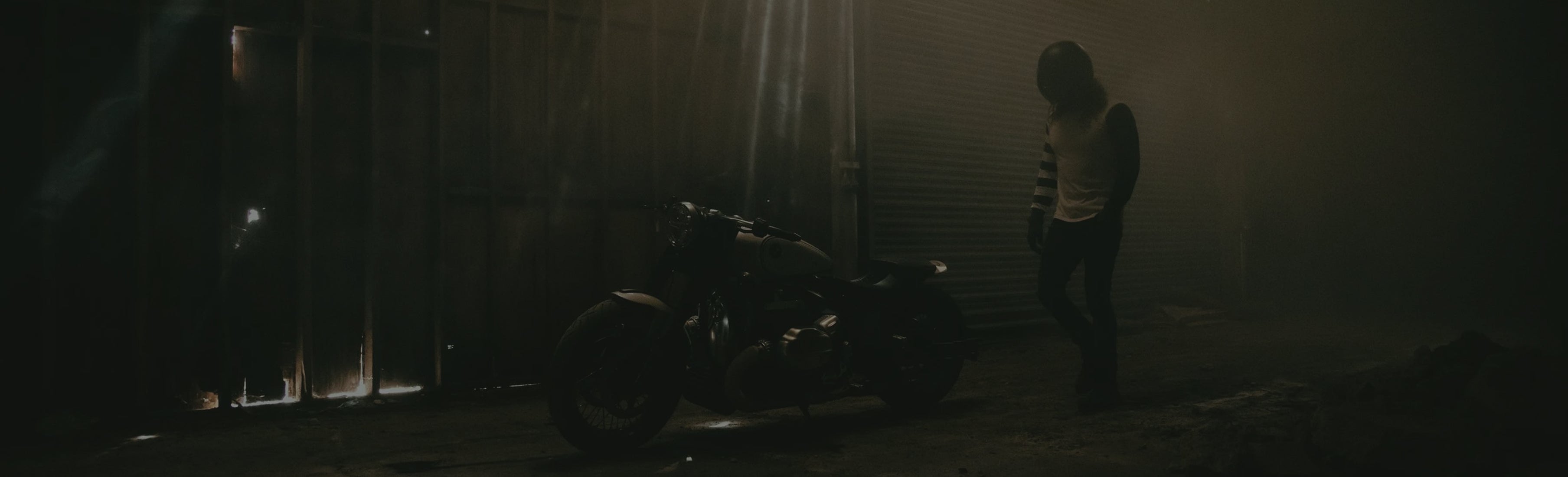 Person standing next to a motorcycle in a dimly lit room