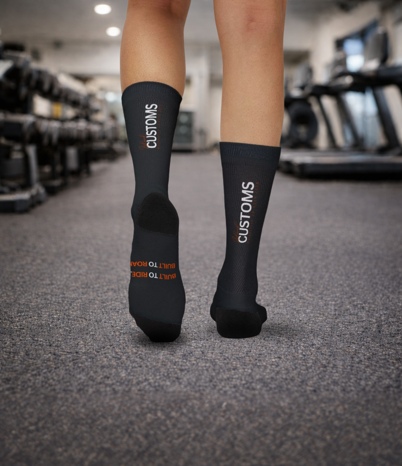 Black socks with 'CUSTOMS' branding worn in a gym setting