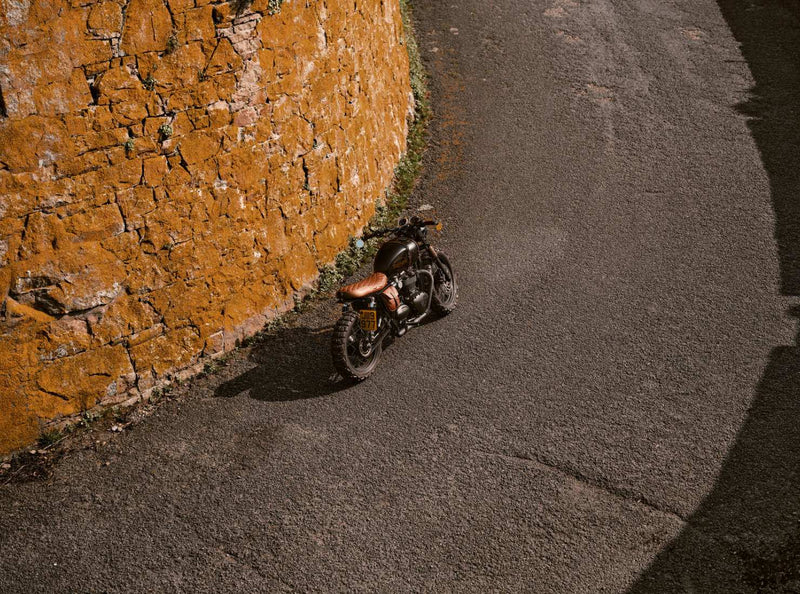 Motorcycle parked on a road next to a textured wall